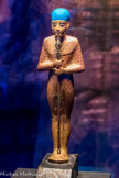 Statue de Ptah en bois doré
Ptah porte une coiffé en verre bleu cobalt. Les trois hiéroglyphes que l'on voit sur son sceptre sont le signe ânkh (la vie), le pilier djed (la stabilité), ainsi que le signe ouas (la puissance).
Bois, gesso, feuille d'or, résine noire, faïence égyptienne bleue, verre (yeux)